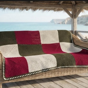 May include: A rectangular crochet blanket featuring a checkered pattern of dark olive green, deep burgundy, and cream white squares. The blanket is finished with a delicate, small-scale white border along the edges, showcasing a classic granny square stitch construction throughout the entire piece.