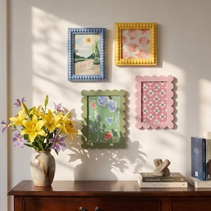 Puede incluir: Cuatro marcos de pared rectangulares en azul, amarillo, verde y rosa, con bordes de cuentas o festoneados. Los marcos contienen láminas artísticas de un paisaje con cisnes, rosas, un patrón floral y un diseño geométrico en la pared.