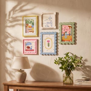 Op de afbeelding: Een verzameling van vijf decoratieve wandlijsten in diverse kleuren en vormen, waaronder gele en witte kralenlijsten, en roze, blauwe en groene geschulpte lijsten, elk voorzien van een unieke, kleurrijke illustratie.