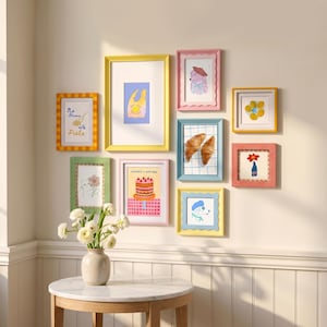 Pode incluir: Uma coleção de obras de arte emolduradas em vários tamanhos e cores, incluindo amarelo, rosa e verde. As obras de arte apresentam ilustrações de comida, flores e um cão. Uma moldura tem o texto "No Drama Only Pasta."