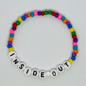 May include: A colorful beaded bracelet with white letter beads spelling out "INSIDE OUT".