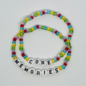May include: Two colorful beaded bracelets with the words "CORE MEMORIES" spelled out in white beads.