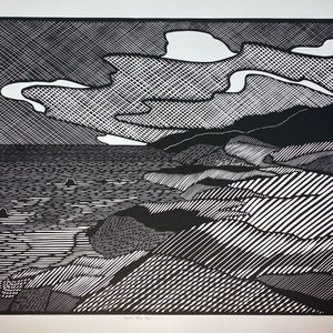 May include: Black and white woodcut print of a coastal landscape with a rocky shoreline, ocean waves, and a cloudy sky. The print is made with a variety of lines and patterns.