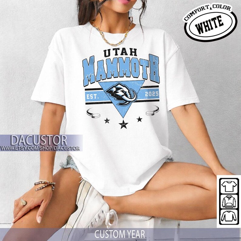 K&ouml;nnte beinhalten: Wei&szlig;es T-Shirt mit dem Text "Utah Mammoth" in Hellblau, einer dreieckigen Grafik und dem Text "EST. 2025". Das Shirt hat auch die Worte "Comfort, Color, White" in einem Kreis. Das Shirt ist ein individuelles Jahresdesign.