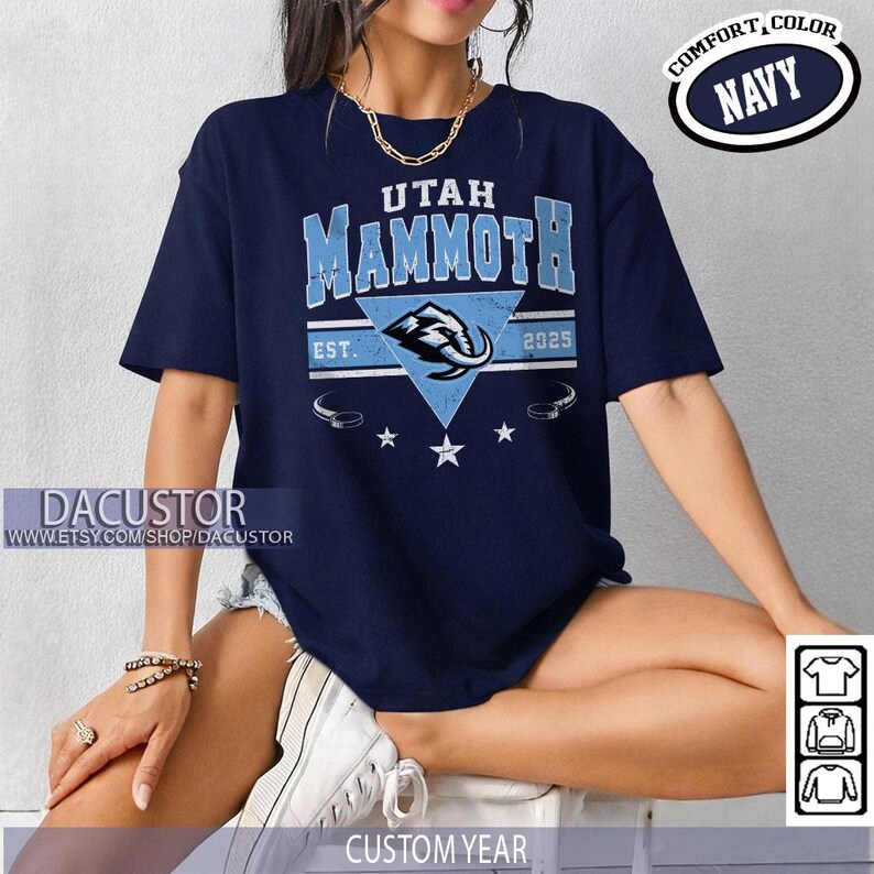 K&ouml;nnte beinhalten: Marineblaues T-Shirt mit dem Text "UTAH MAMMOTH" und einer hellblauen Mammut-Grafik. Das Shirt zeigt auch "EST. 2025" und die Worte "COMFORT, COLOR NAVY". Der Etsy-Shop-Name "DACUSTOR" ist sichtbar.