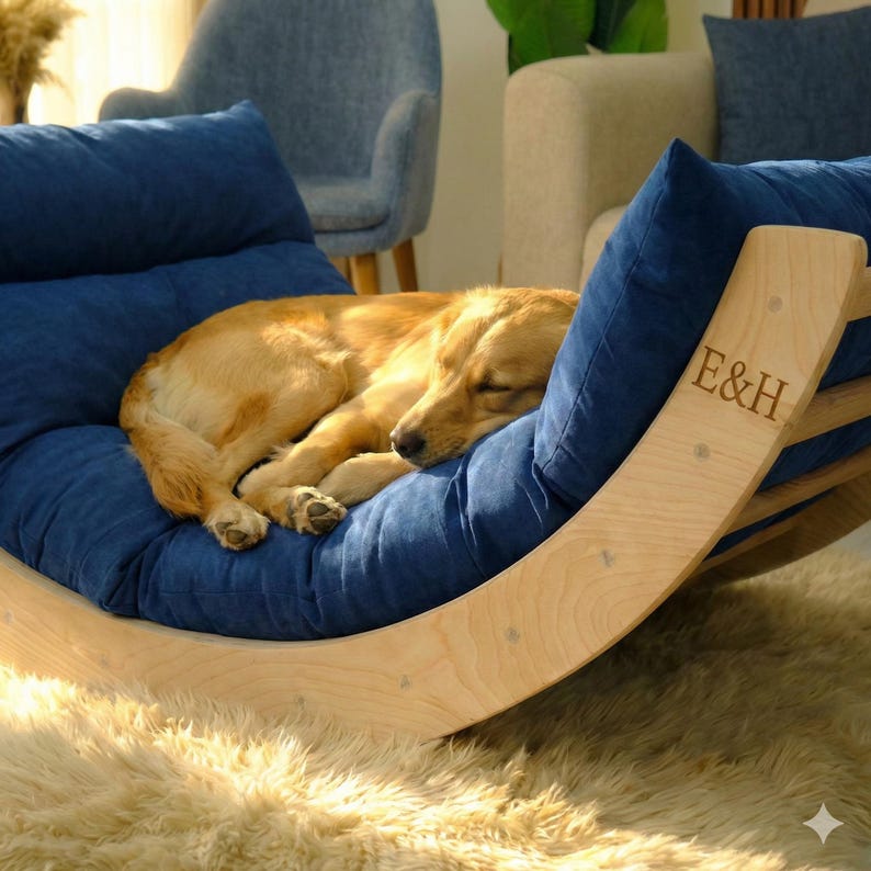 A golden retriever dog is curled up and sleeping on a blue cushion with the letters "E&H" carved into it.