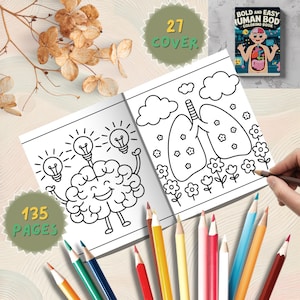 K&ouml;nnte beinhalten: Ein offenes Malbuch mit Illustrationen des menschlichen K&ouml;rpers, darunter ein Gehirn mit Gl&uuml;hbirnen und Lungen mit Blumen. Auf dem Cover steht "Bold and Easy Human Body Coloring Book". Farbstifte umgeben das Buch. Das Buch hat 135 Seiten und 27 Cover.