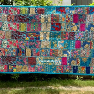 May include: A large, rectangular patchwork textile with a turquoise border. The patchwork design features a variety of colorful, patterned fabrics in shades of blue, pink, red, and gold. The text "Shivaayfashion" is visible on the textile.