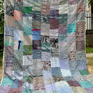 May include: A patchwork quilt with a variety of fabric patterns and colors, including blue, green, purple, and brown. The quilt is made of rectangular patches sewn together with visible stitching. The text "ShivaayFashion" is visible on the quilt.