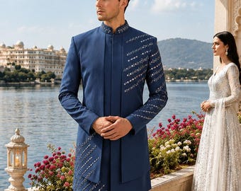 Puede incluir: Un sherwani azul profundo con cuello mao y mangas largas, adornado con filas diagonales de espejos plateados en el hombro izquierdo y el panel inferior derecho, combinado con pantalones ajustados a juego y zapatos de vestir de cuero marrón oscuro.