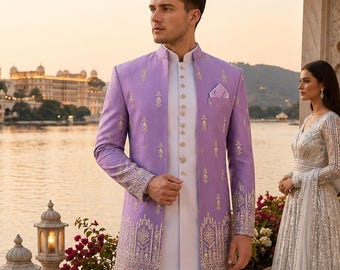 Puede incluir: Una chaqueta sherwani de color lavanda con bordados dorados y cuello mao, sobre un kurta blanco y pantalones blancos. La chaqueta tiene un corte estructurado con mangas largas, un pañuelo de bolsillo y patrones intrincados en el dobladillo.