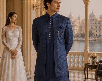 Puede incluir: Un sherwani azul oscuro con un patrón texturizado intrincado, cuello alto y una hilera de botones plateados. El conjunto incluye una túnica larga a juego, pantalones ajustados y mocasines azul oscuro, con un broche de cadena plateado.