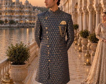 Puede incluir: Un sherwani azul oscuro con un patrón floral dorado repetitivo, cuello alto y dobladillo asimétrico. La prenda se combina con pantalones blancos lisos y mocasines azul oscuro. Incluye un pañuelo de bolsillo dorado y un broche de cadena.