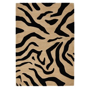 Pu&ograve; includere: Un tappeto rettangolare con sfondo beige e un audace motivo a strisce zebrate nere. Il design del tappeto presenta spesse strisce nere irregolari che creano un contrasto sorprendente sullo sfondo neutro. Un elemento di arredo per la casa.