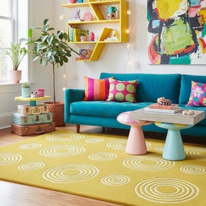 May include: A living room scene featuring a teal sofa with colorful throw pillows, a yellow rug with white concentric circles, and a unique coffee table. A yellow shelf and artwork add to the room's vibrant decor. Plants and stacked suitcases add to the room's charm.