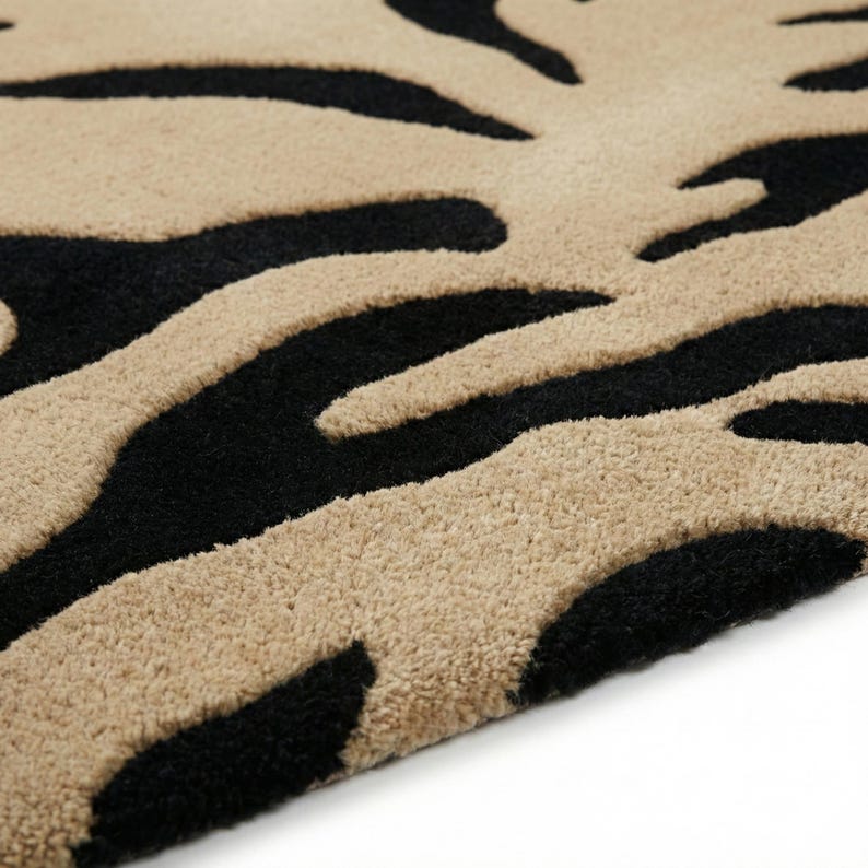 Pu&ograve; includere: Primo piano di un tappeto beige e nero con un motivo a strisce zebrate. Il tappeto ha una superficie morbida e strutturata e una palette di colori neutri, adatta a vari stili di interior design.