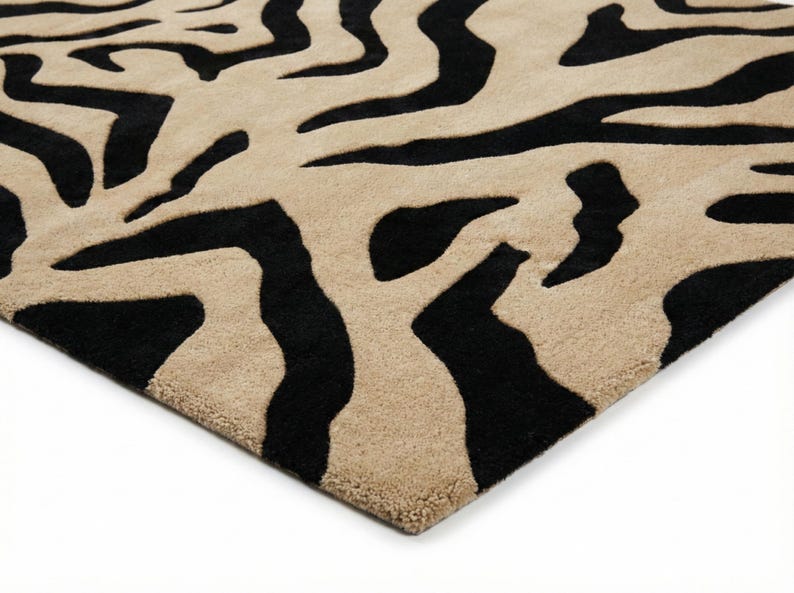 Pu&ograve; includere: Un tappeto beige e nero con un motivo a strisce zebrate. Il tappeto ha una superficie morbida e strutturata e una palette di colori neutri, adatta a vari stili di interior design. Le strisce nere creano un contrasto audace con lo sfondo beige.
