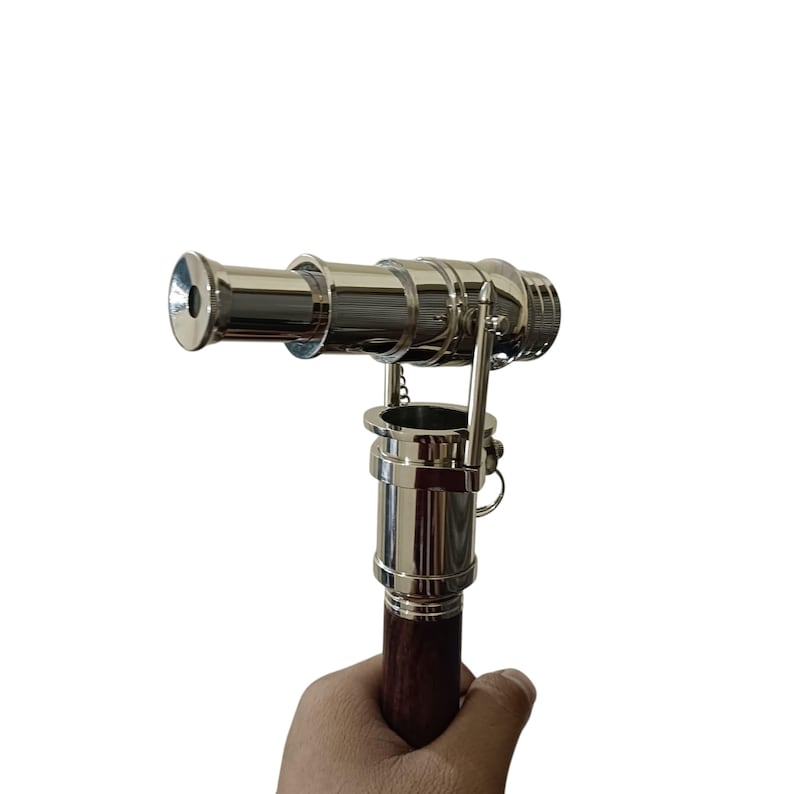 Pu&ograve; includere: Un telescopio argentato lucido con un manico in legno marrone scuro. Il telescopio &egrave; tenuto in mano ed &egrave; progettato con una classica estetica nautica. Il telescopio &egrave; lungo circa 30 cm.