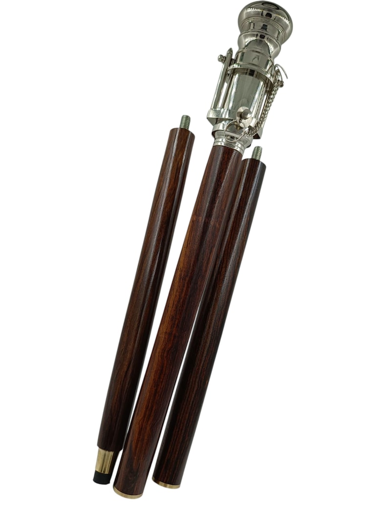 Pu&ograve; includere: Un bastone da passeggio in legno marrone scuro con manico e dettagli in metallo color argento. Il bastone &egrave; parzialmente smontato, con tre sezioni di legno separate visibili. L'impugnatura ha un design decorativo e una piccola catena.