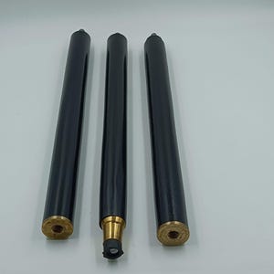 以下が含まれることがあります： 真鍮色の金属アクセントが付いた、黒い木製の家具の脚が3本。脚は円筒形で、取り付け用のねじ付き端があります。画像は白い背景に対して撮影されています。