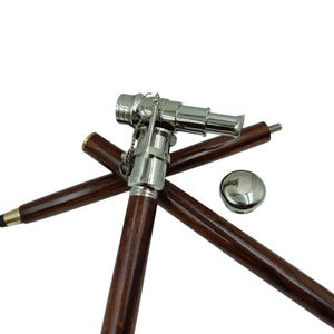Pu&ograve; includere: Bastone da passeggio in stile vintage con un'asta in legno marrone scuro e un'impugnatura argentata a forma di telescopio. Il bastone ha un tappo argentato rimovibile e una punta nera. Progettato per supporto e stile.