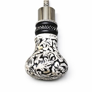 May include: Decorative bottle stopper with a black and white floral design. The stopper has a silver metal top and a textured, bulbous base. The base is painted with a detailed, swirling pattern. A unique addition to any barware collection.
