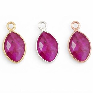 Puede incluir: Tres colgantes de piedras preciosas con una piedra de color magenta facetada en forma de marquesa. Los engastes son dorados, plateados y oro rosa. Cada colgante tiene un pequeño lazo en la parte superior para sujetarlo a una cadena u otro componente de joyería.