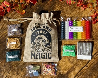May include: A burlap bag with the text "MAKE YOUR OWN MAGIC" and various items for spell crafting. Includes small bags of herbs, crystals, mini spell candles, and a box of matches. The items are arranged on a wooden surface.