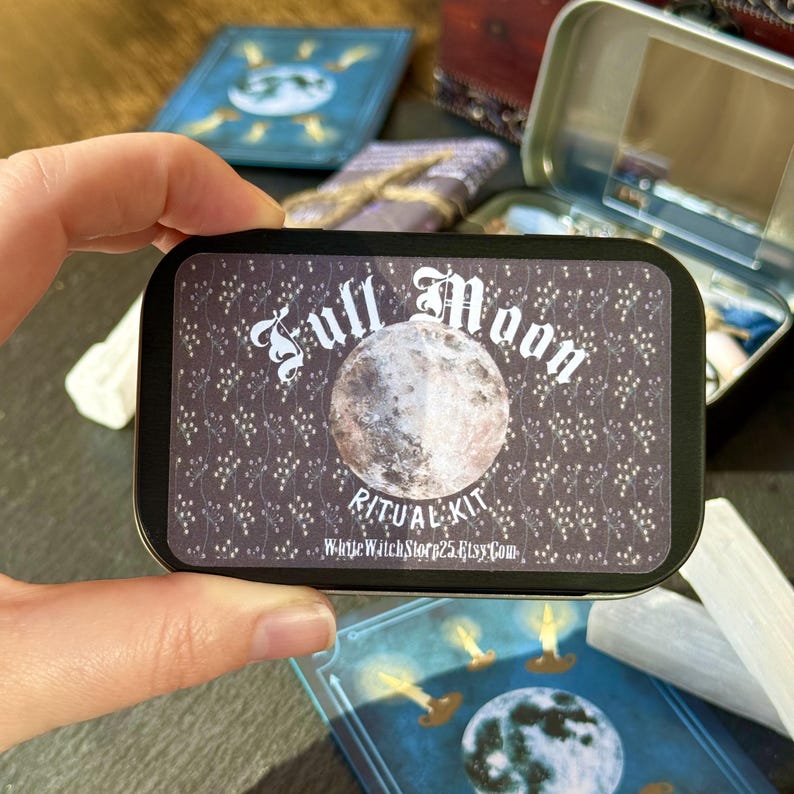 May include: A rectangular tin with a black background and the words "Full Moon Ritual Kit" in white script. The tin features a detailed image of the moon. Other items are visible in the background.