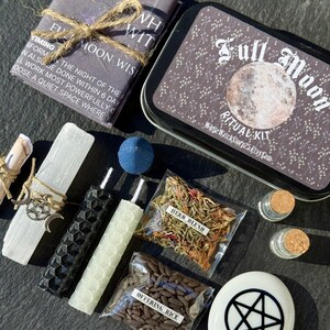 May include: A Full Moon Ritual Kit with various components. Includes a tin with "Full Moon Ritual Kit" text, candles, herbs, offering rice, and a stone with a pentagram. The kit is tied with twine and has a scroll and a blue sphere.