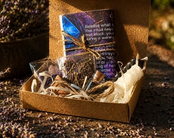 May include: A brown cardboard box containing a ritual kit with a printed instruction card, a small clear plastic bag of dried lavender, a tiny glass vial with a cork stopper, a small bag of purple crystals, and white paper filler shreds.