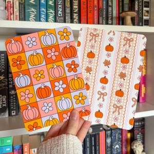 Könnte beinhalten: Zwei rechteckige Karten mit Herbstmotiven. Die linke Karte zeigt ein Gitter aus orangefarbenen, rosafarbenen und hellvioletten Quadraten mit Kürbissen und Blumen. Die rechte Karte hat vertikale Streifen mit Vichy-Muster, Schleifen und Kürbissen.