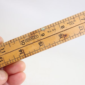 May include: A vintage wooden folding ruler with a natural light brown finish and black printed markings. The ruler features the Stanley brand logo, the text No. 68, and the phrase MADE IN U.S.A. It displays imperial measurements in inches.
