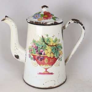 May include: Vintage white enamelware coffee pot with a floral lid and a fruit-filled bowl design. The pot has a spout, handle, and lid. The fruit bowl features grapes and other fruits in shades of red, yellow, and green.