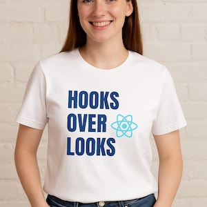 Peut inclure: T-shirt blanc avec le texte "HOOKS OVER LOOKS" en bleu, accompagné d'un symbole d'atome bleu. La personne porte un jean bleu. L'arrière-plan est un mur de briques blanches.