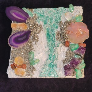 May include: A white square canvas with a green, white, and gold abstract design. The canvas is decorated with various purple, pink, and green gemstones.