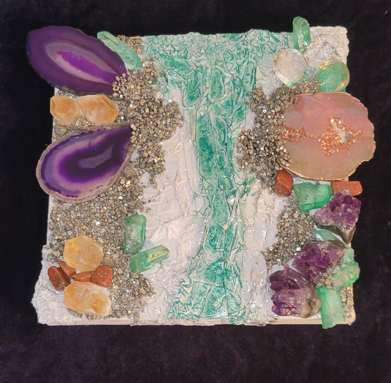 May include: A white square canvas with a green, white, and gold abstract design. The canvas is decorated with various purple, pink, and green gemstones.