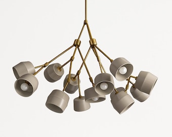 May include: Modern chandelier with multiple light fixtures. The light fixtures are a light gray color and are arranged in a cluster. The arms are a brass color. The light bulbs are visible inside the fixtures.