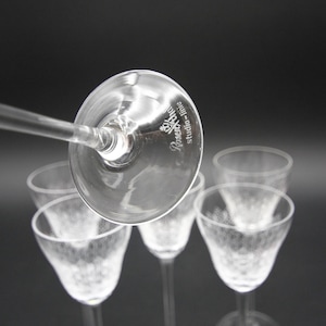 May include: A collection of clear, stemmed glasses with a delicate, textured design. The glasses have a slender stem and a flared bowl. The text "Rosenthal studio-linie" is visible on the bottom of one glass. The background is a solid black.