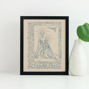 May include: Framed art print featuring a blue line drawing of two figures with halos, surrounded by floral and leaf border. A dove is above the figures. The artwork is in a black frame, and a white vase with a green leaf is next to it.