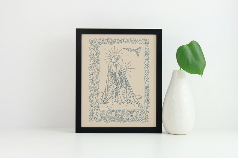 May include: Framed art print featuring a blue line drawing of two figures with halos, surrounded by floral and leaf border. A dove is above the figures. The artwork is in a black frame, and a white vase with a green leaf is next to it.