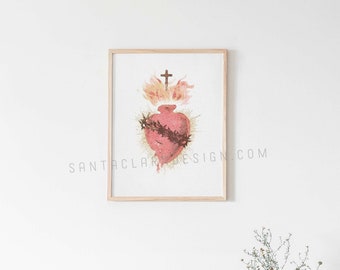 May include: A framed print of a vintage illustration of a heart with a crown of thorns and a cross above it. The heart is red and the background is white.