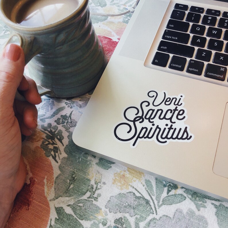 Puede incluir: Un port&aacute;til blanco con un teclado negro y una pegatina en blanco y negro que dice "Veni Sancte Spiritus".