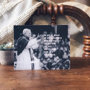 May include: Black and white photo of Pope John Paul II with a quote: "Do not be afraid. Do not be satisfied with mediocrity. Put out into the deep and let down your nets for a catch." Saint John Paul II.