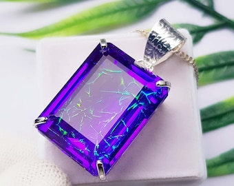 May include: A rectangular purple pendant featuring a faceted surface with internal crackle patterns in neon green and blue. The gemstone is set in a silver-toned metal prong setting with a textured bail attached to a delicate silver-toned chain.