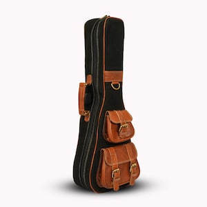 Puede incluir: Funda de guitarra negra con detalles en cuero marrón y dos bolsillos delanteros. La funda tiene un asa, una anilla en D y cierre de cremallera. Diseñada para proteger una guitarra durante el transporte.