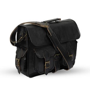 May include: Black leather messenger bag with multiple pockets and brass-colored buckles. Features a top handle and adjustable shoulder strap. The bag has a rectangular shape and a flap closure.