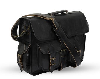 May include: Black leather messenger bag with multiple pockets and brass-colored buckles. Features a top handle and adjustable shoulder strap. The bag has a rectangular shape and a flap closure.