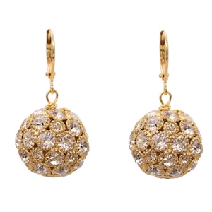 May include: A pair of gold dangle earrings with a round, sparkly, clear crystal ball design.