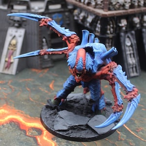 Puede incluir: Figura en miniatura de una criatura azul y roja. Tiene garras afiladas y un rostro amenazante, colocada sobre una base negra. Ideal para juegos de mesa o coleccionistas.
